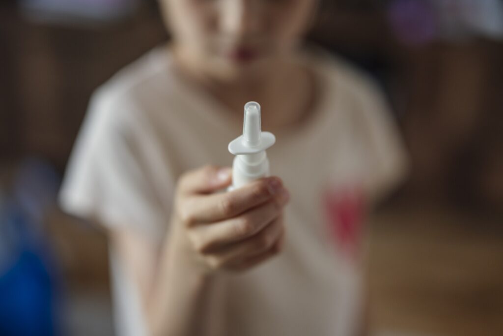 Flacon de spray nasal posé sur une tablette de salle de bains, bouchon retiré à côté