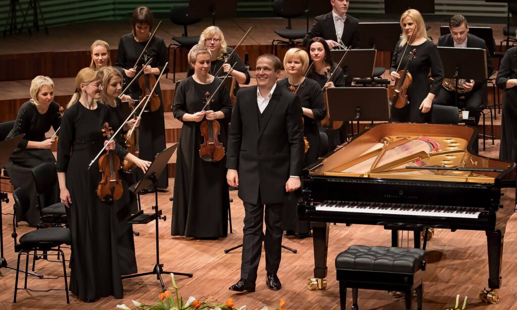 Orchestre en train de s’accorder avant un concert, pupitres allumés et salle encore vide