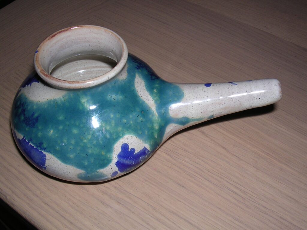 Pot de rin&ccedil;age nasal en c&eacute;ramique claire pos&eacute; pr&egrave;s d&rsquo;un lavabo, bec verseur tourn&eacute; de c&ocirc;t&eacute;