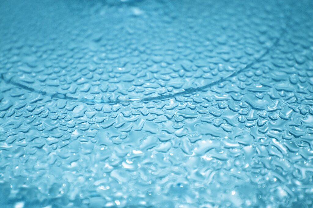 Verre d’eau à moitié plein posé au bord d’une table en bois clair