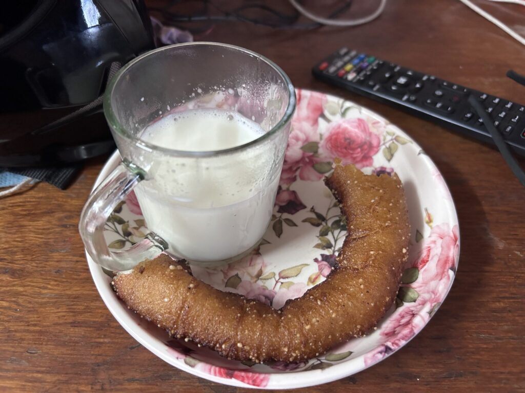 Grains de kéfir de lait blancs retenus dans une passoire en plastique au-dessus d’un bol