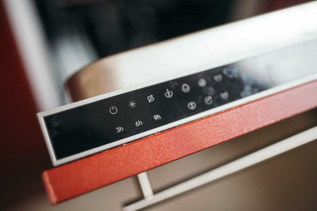 Minuteur m&eacute;canique pos&eacute; au sol pr&egrave;s d&rsquo;un tapis, aiguille r&eacute;gl&eacute;e sur quelques minutes