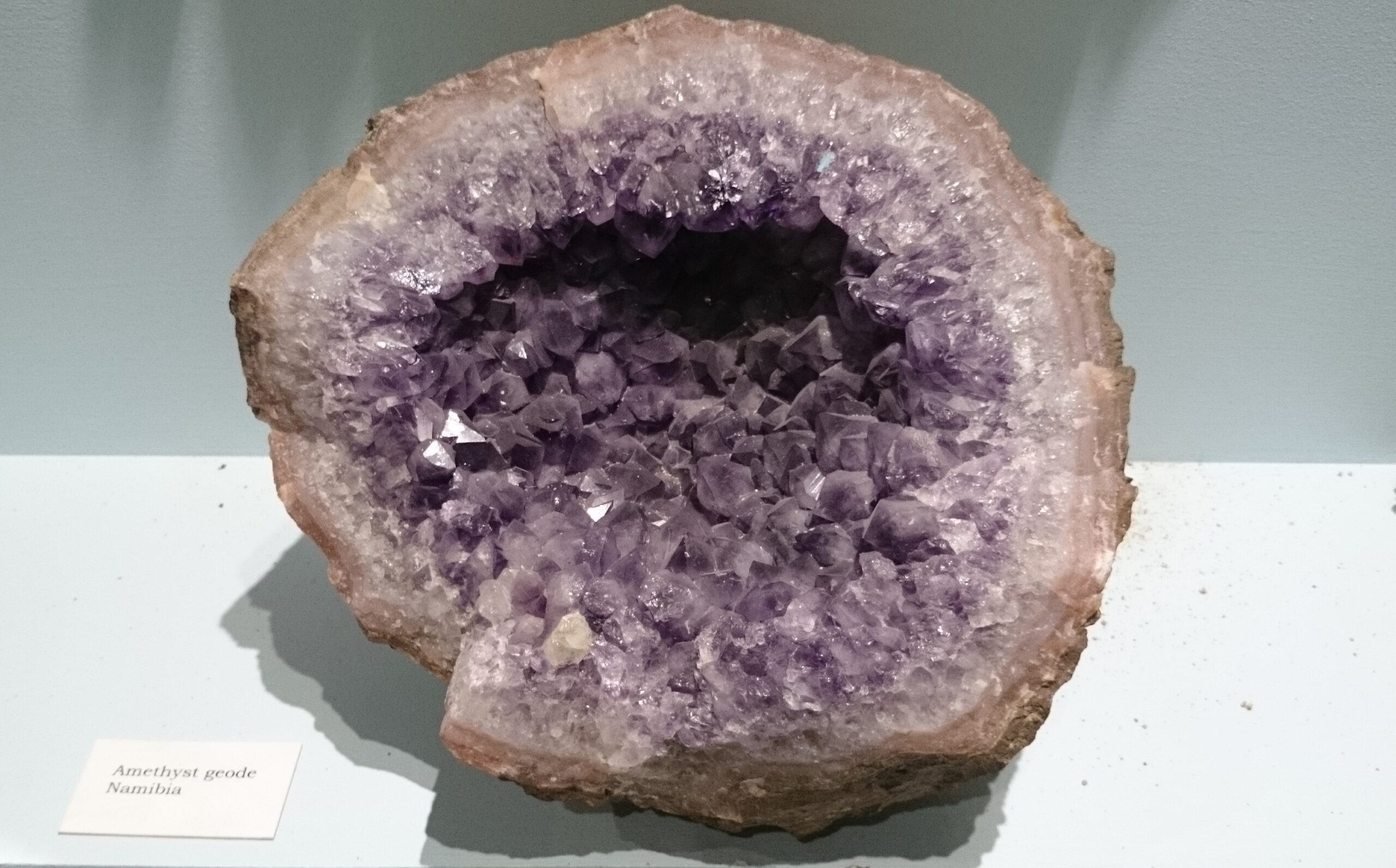 Géode d’améthyste ouverte, cristaux violets serrés tapissant une cavité rocheuse claire