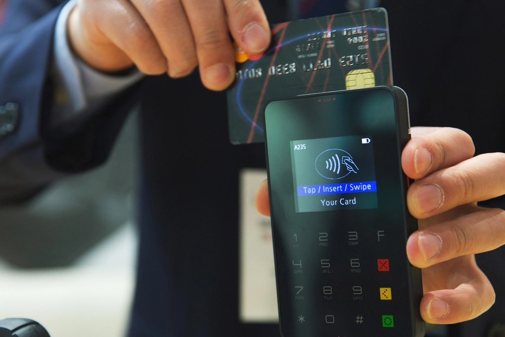 Carte bancaire tenue devant un écran de téléphone au moment de valider un paiement