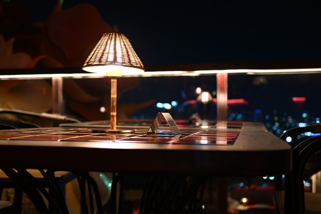 Lampe de table &agrave; abat-jour en tissu pos&eacute;e sur un meuble bas, ampoule ambr&eacute;e allum&eacute;e