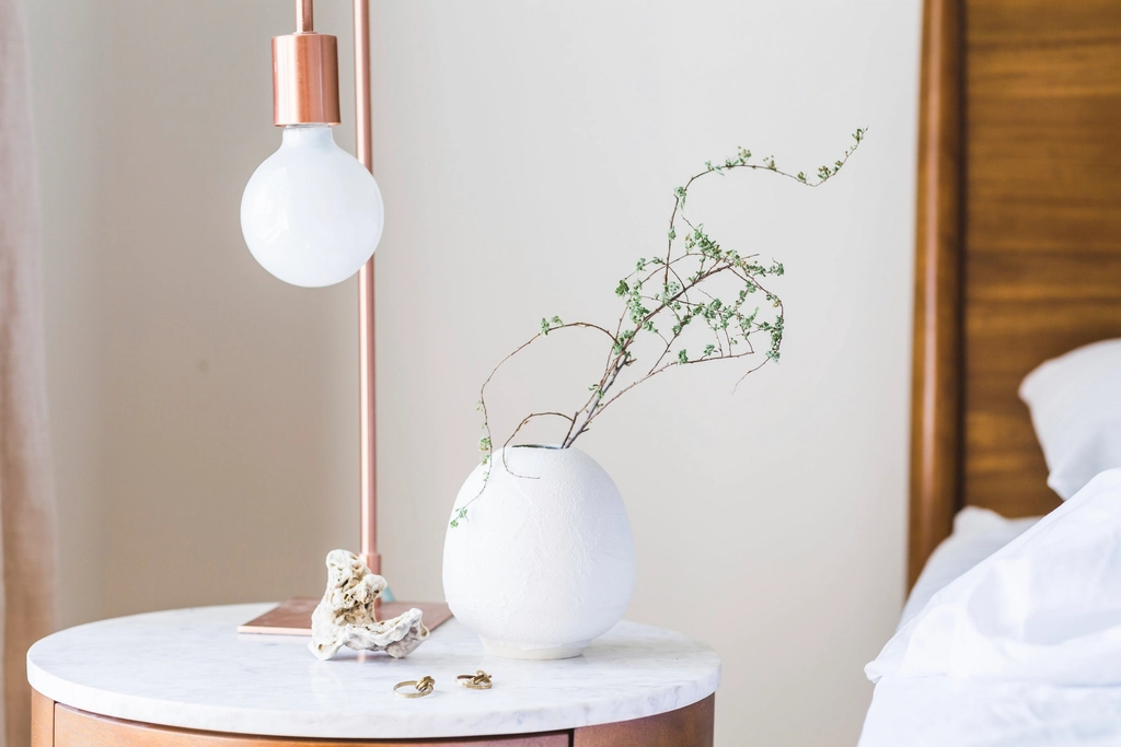 Lampe de chevet allum&eacute;e sur une table basse, chambre plong&eacute;e dans la p&eacute;nombre